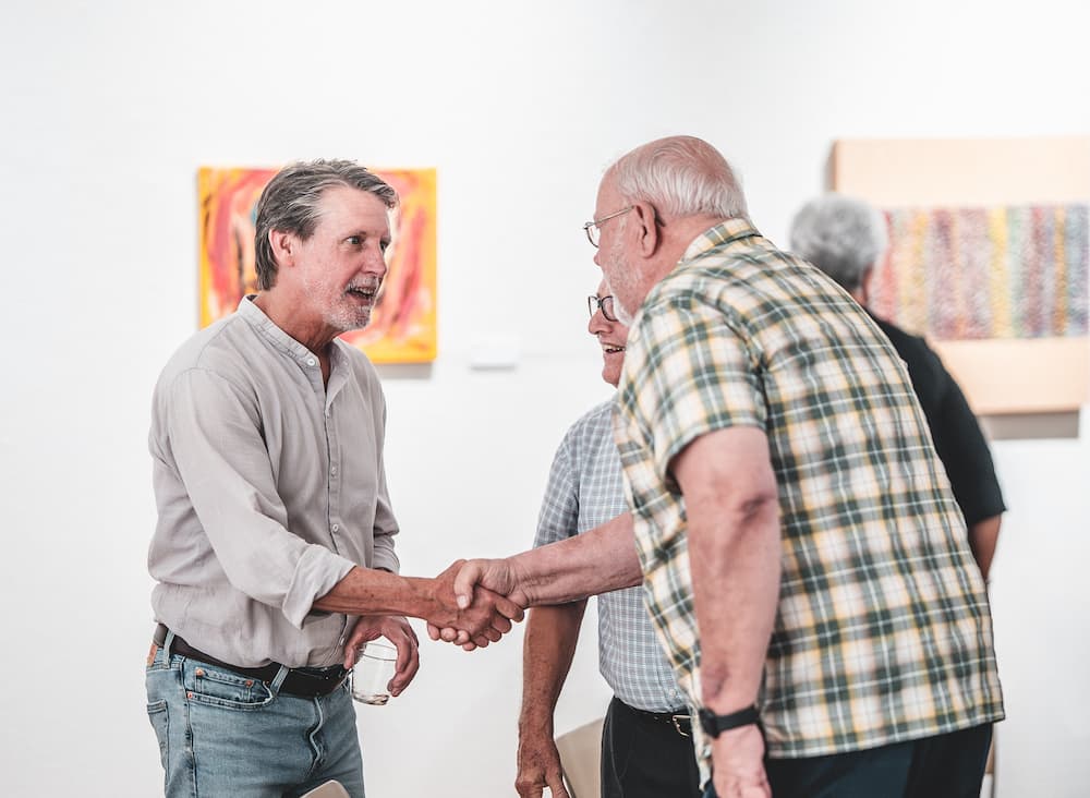 Men shaking hands at art show